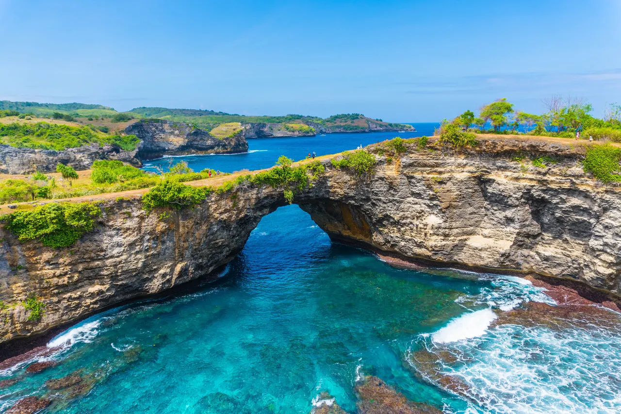 The natural rock archway at Broken Beach, Nusa Penida, with turquoise water in the circular cove below.